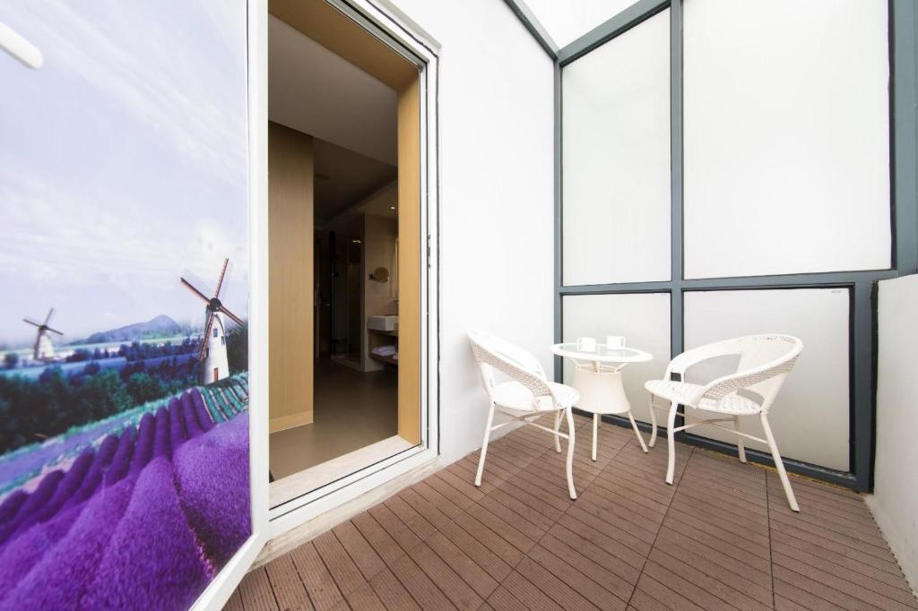 a balcony with white chairs and a table and windmills at Lavande Hotels·Kunshan Renmin Road in Suzhou