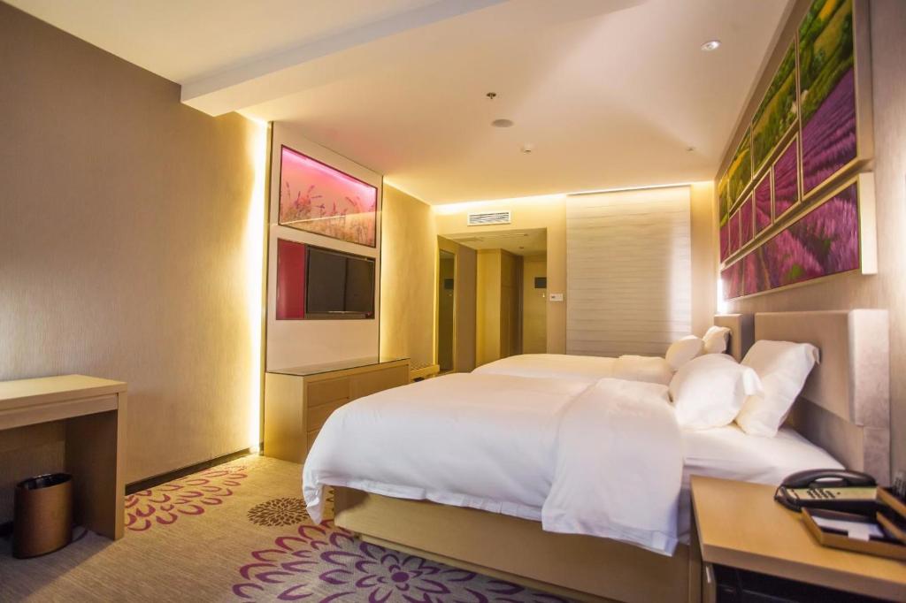 ein Schlafzimmer mit einem großen weißen Bett und einem Schreibtisch in der Unterkunft Lavande Hotels·Guilin MixC in Guilin
