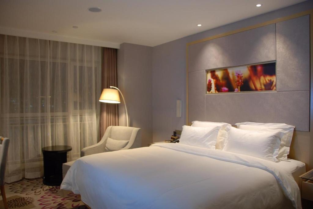 a bedroom with a large white bed and a chair at Lavande Hotels·Xian High-Tech Zone West Avenue Yango in Xi'an