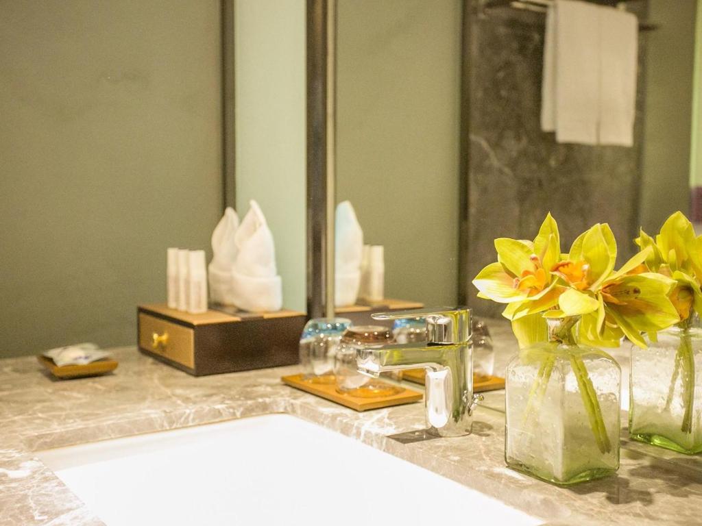 a bathroom counter with a vase of flowers and a mirror at Lavande Hotels·Guangzhou East Railway Station in Guangzhou