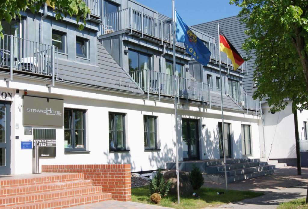 ein Gebäude mit zwei Flaggen davor in der Unterkunft Strandhotel Dranske in Dranske