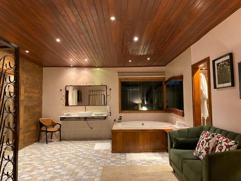 a bathroom with a tub and a couch in a room at Estalagem Alter Real in Pirenópolis