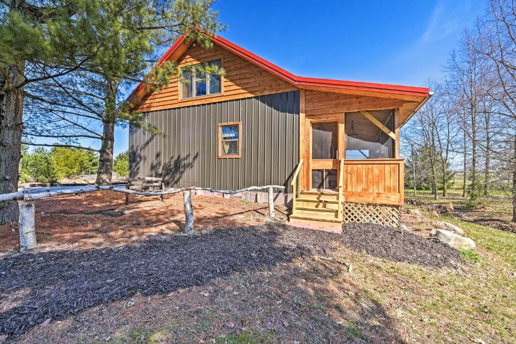 una pequeña casa con techo rojo en una colina en Honey House Cabin - A Quiet Countryside Retreat!, en Nappanee