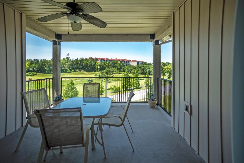 a screened porch with a table and chairs and a ceiling fan at Links at Thousand Hills in Branson