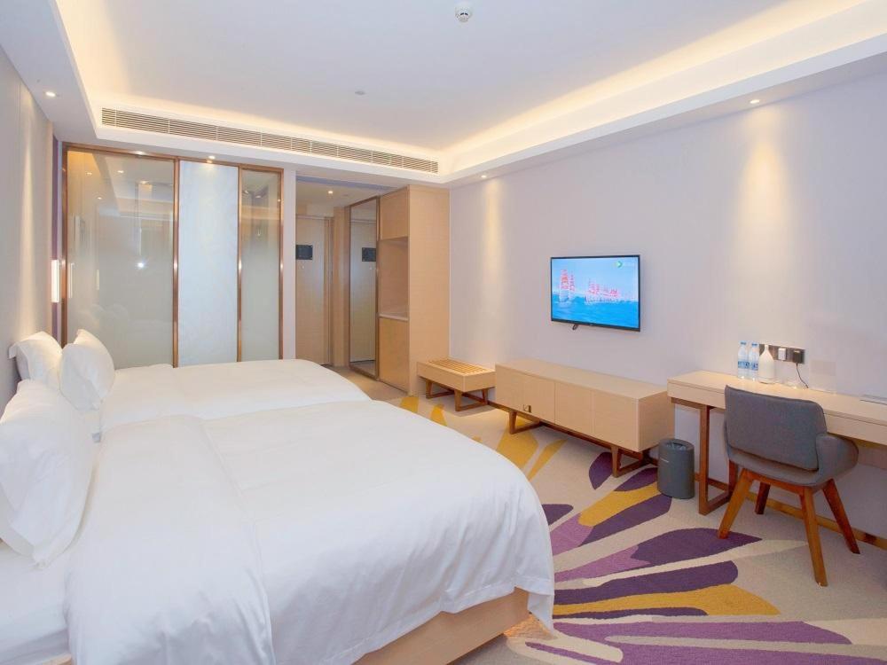 a bedroom with a white bed and a desk and a computer at Lavande Hotels·Nanjing South of Olympic Stadium Daishan New Town in Nanjing