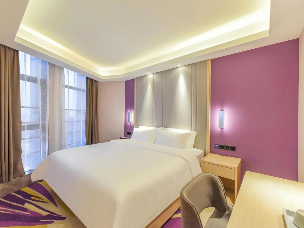 重慶市にあるLavande Hotel Chongqing Nanping Pedestrian Street Convention and Exhibition Centerの紫の壁のベッドルーム1室(大きな白いベッド1台付)