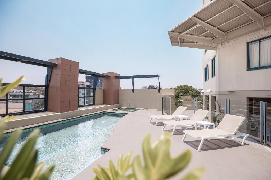a patio with chairs and a swimming pool on a building at Mantra on Queen in Brisbane
