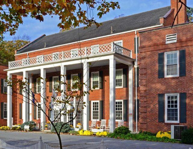 a large red brick building with a white balcony at The Country Inn of Berkeley Springs in Berkeley Springs