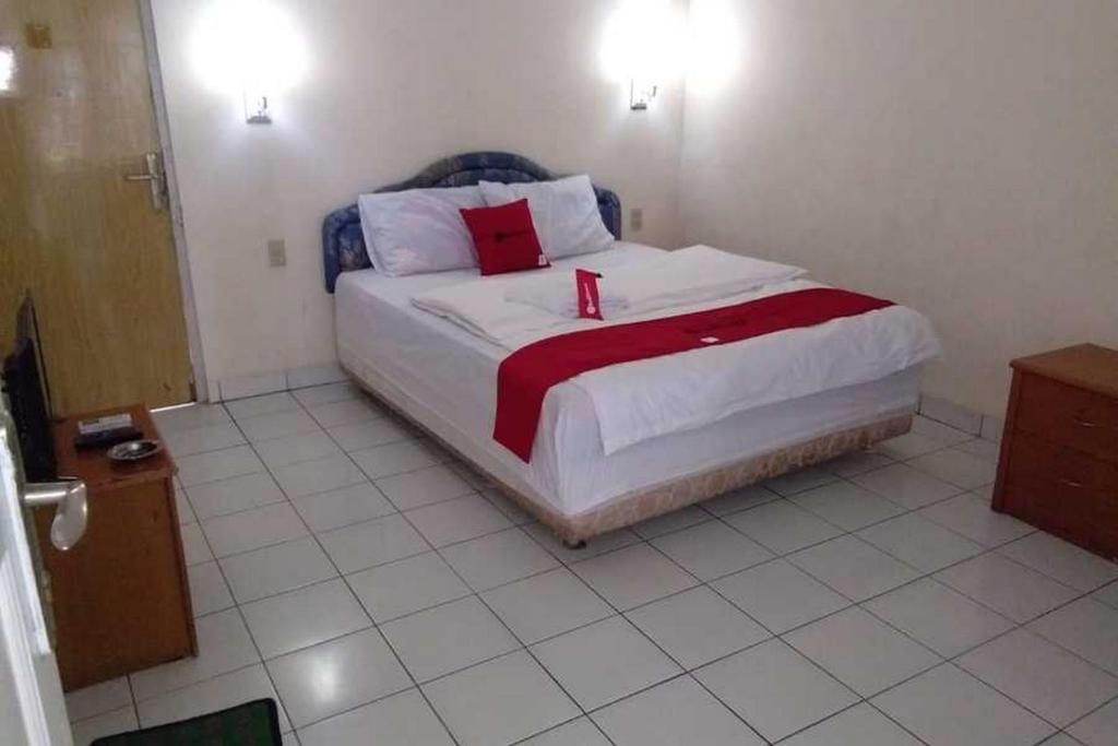 1 dormitorio con 1 cama grande con almohadas rojas y blancas en RedDoorz near Lokawisata Baturaden 2, en Tenjo