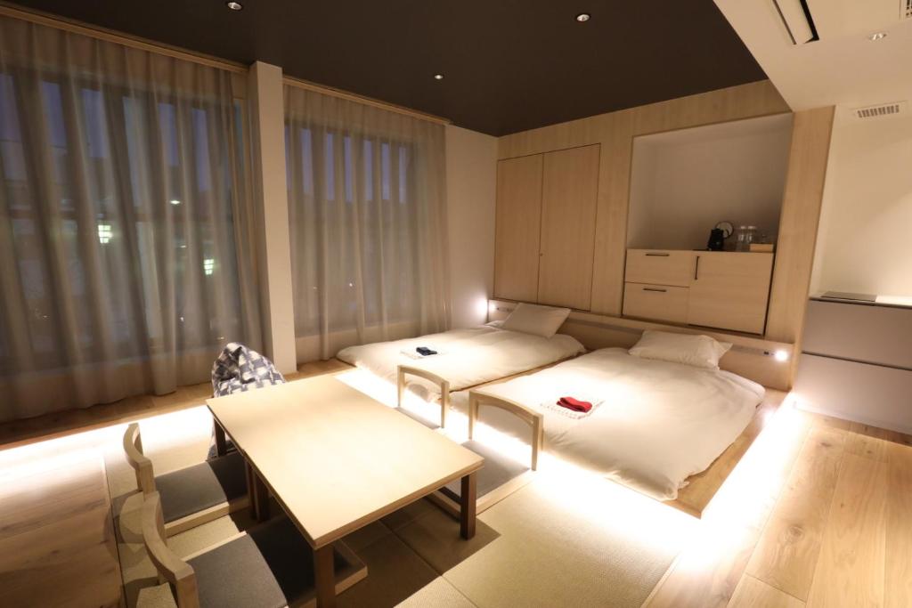 a room with two beds and a table and chairs at GEN HOTEL KAMAKURA in Kamakura
