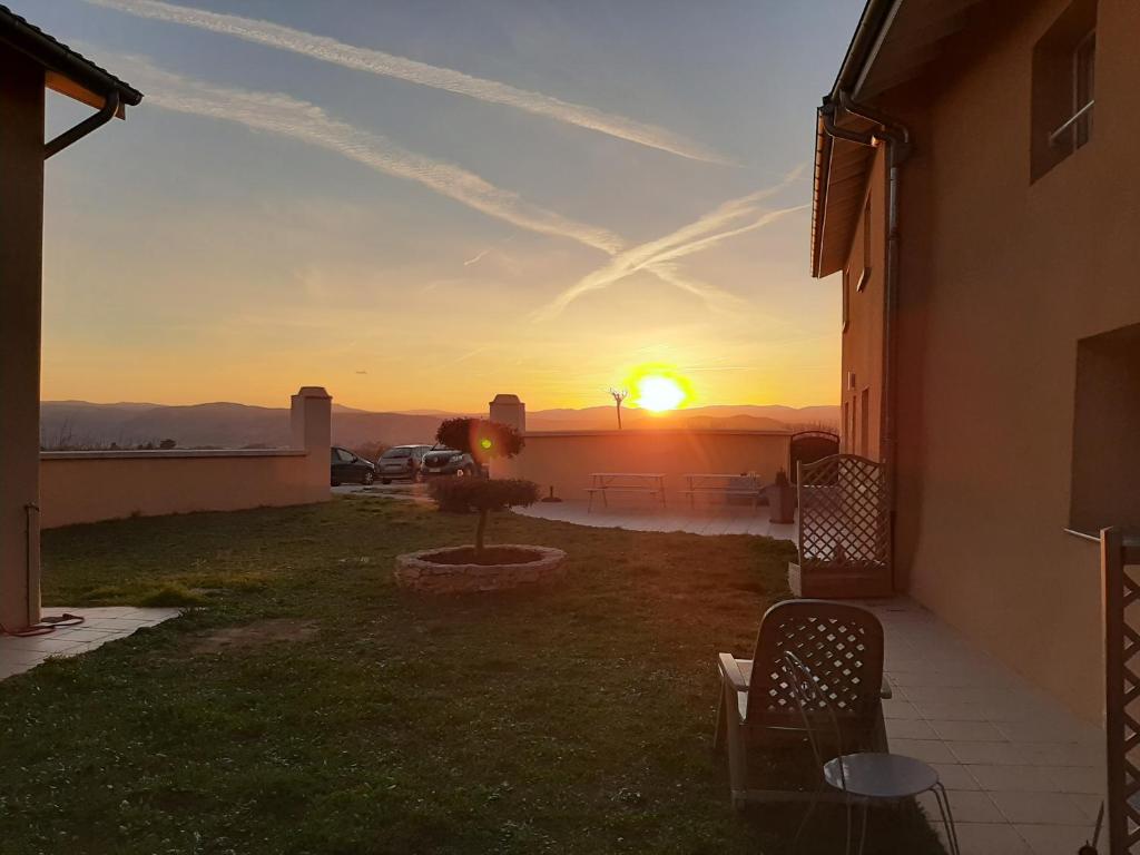 a sunset over a yard with chairs and a house at LE PRESSOIR in Mercurol