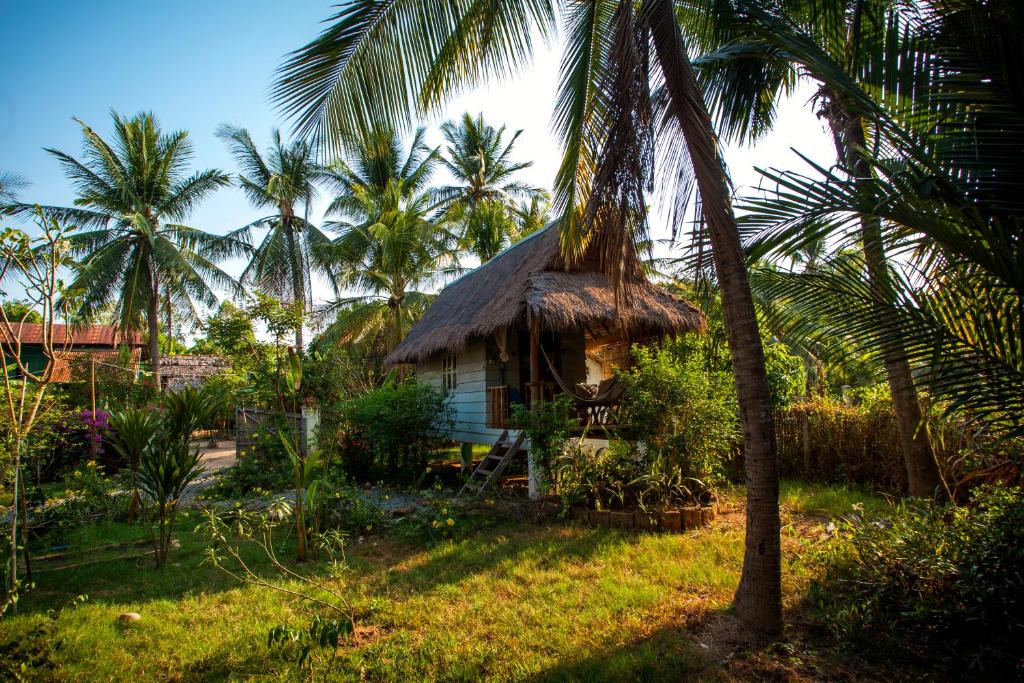 a small hut with a thatched roof and palm trees at Retro Kampot Guesthouse in Kampot
