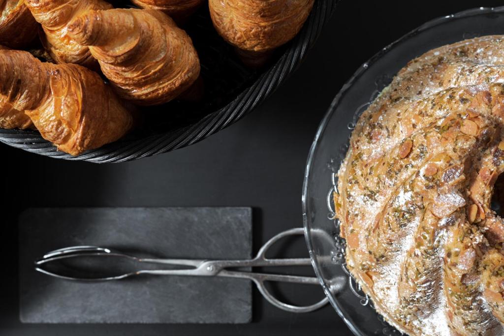 a glass pan with a basket of croissants and a bowl of bread at Castel Beau Site in Perros-Guirec