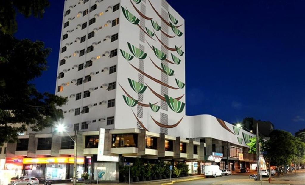 un gran edificio blanco con un árbol. en Copas Verdes Hotel, en Cascavel