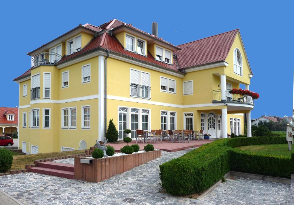une maison jaune avec un aménagement paysager devant elle dans l'établissement Hotel Bachwiesen, à Langensendelbach