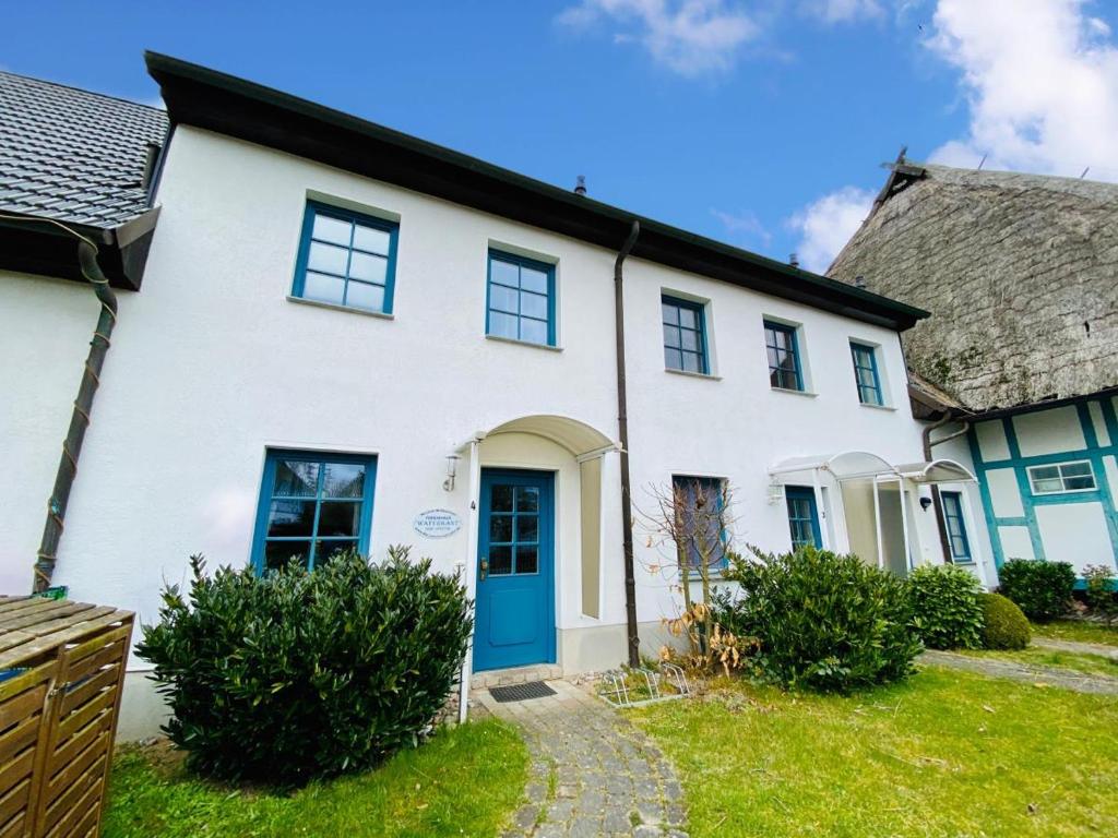 uma casa branca com uma porta azul em Ferienhaus Waterkant em Warnemünde