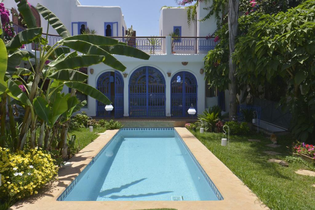 a swimming pool in front of a house at Riad Des Plages in Bouznika