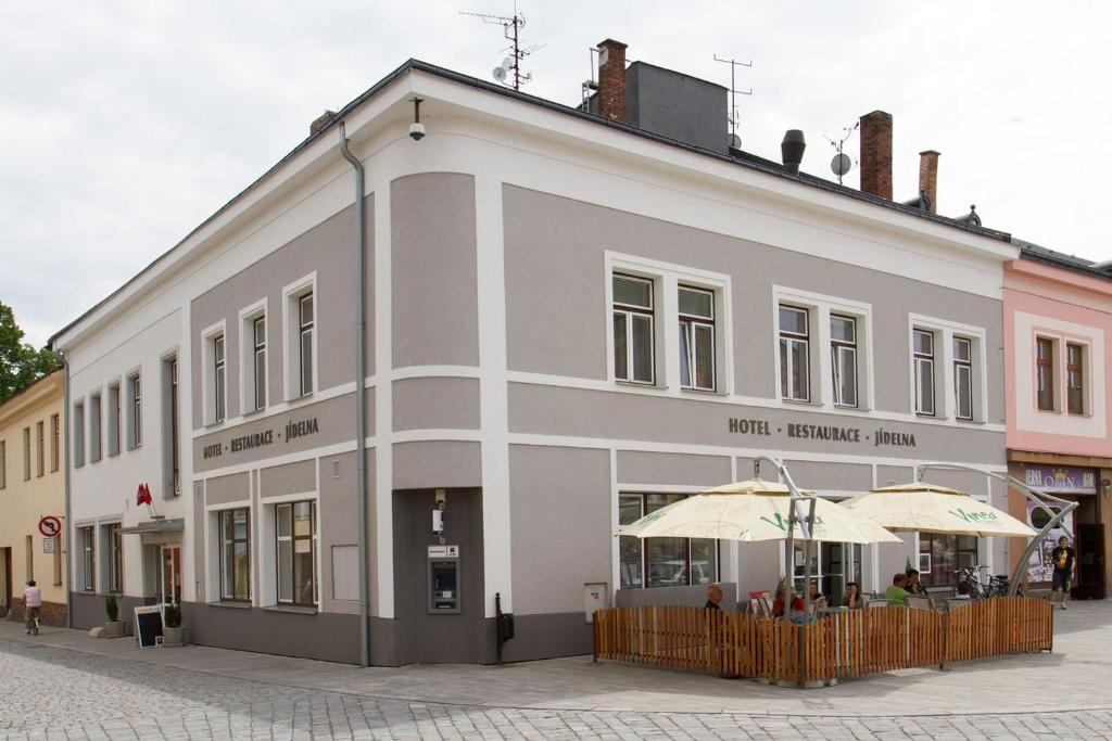 a white building with umbrellas in front of it at Hotel THT in Polička