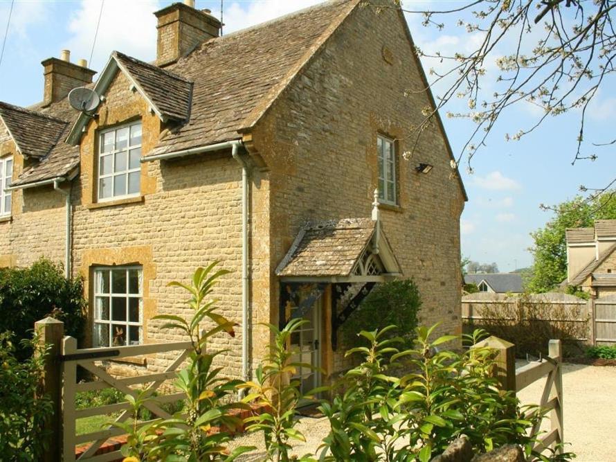 an old brick house with a fence in front of it at Honeysuckle Cottage in Stow on the Wold