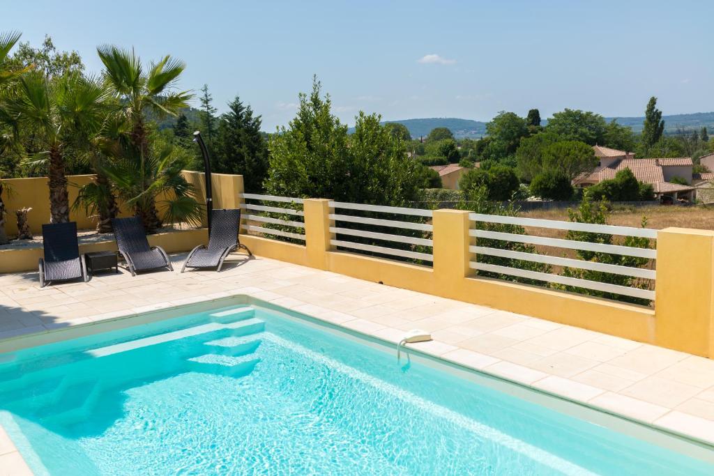 a swimming pool with two chairs and a fence at Villa Vaunage Piscine Chauffée in Langlade