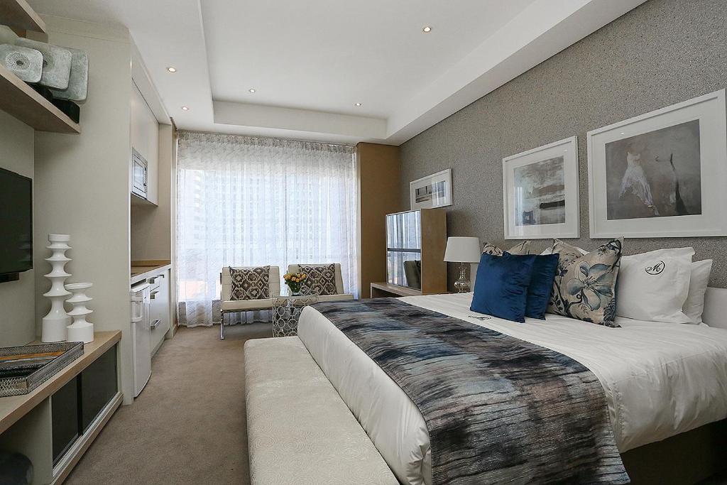 a large bedroom with a large bed with blue pillows at 305 Sandton Skye in Johannesburg