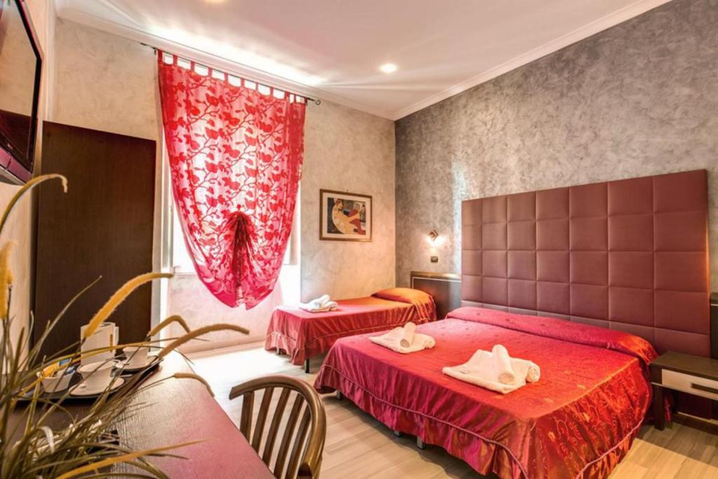 a hotel room with two beds with red sheets at New Inn in Rome