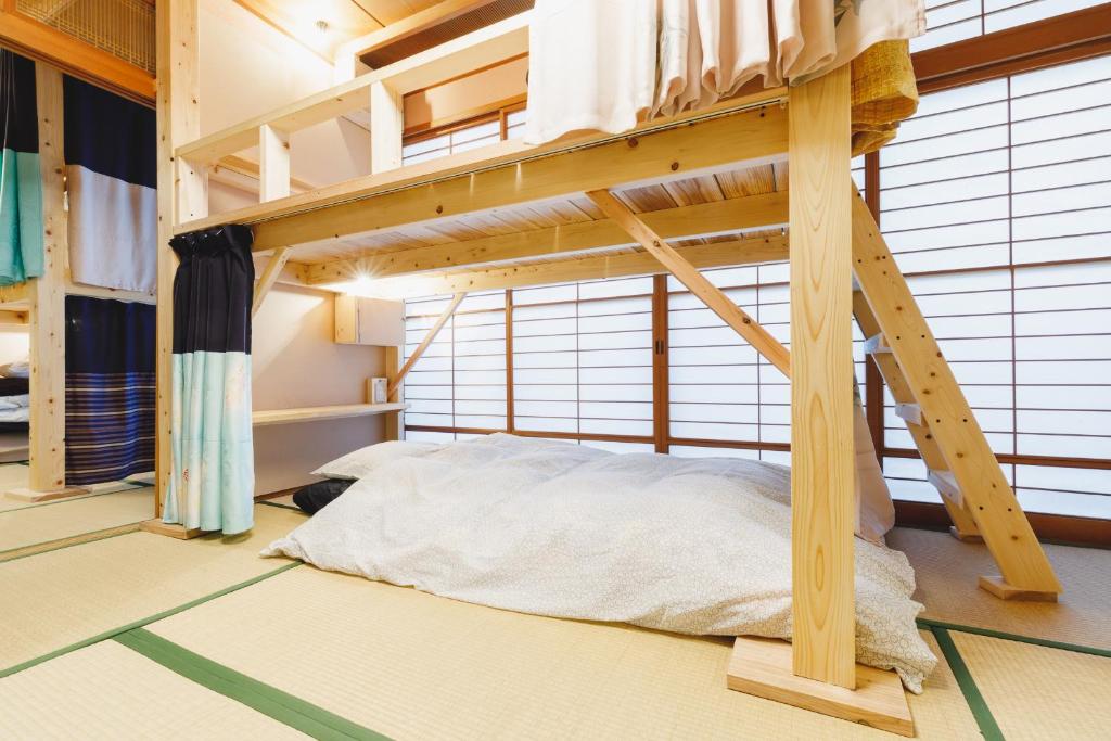 ein Schlafzimmer mit einem Etagenbett in einem Zimmer mit Fenstern in der Unterkunft Couch Potato Hostel in Matsumoto