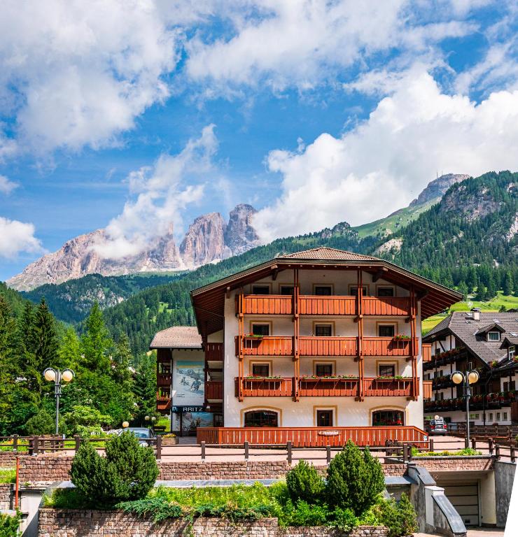 a large building with mountains in the background at Garni Aritz in Campitello di Fassa