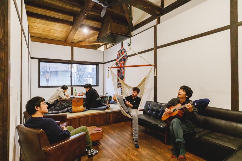 Eine Gruppe von Leuten, die in einem Zimmer Gitarre spielen in der Unterkunft Couch Potato Hostel in Matsumoto