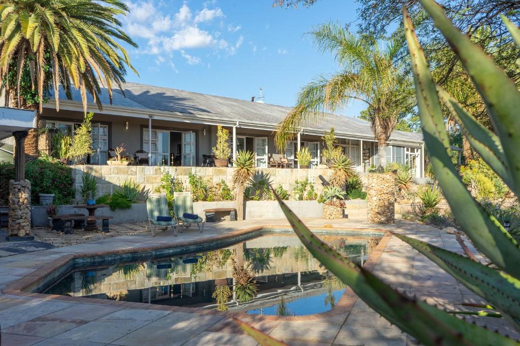 a house with a swimming pool and palm trees at Aloe Manor in Oudtshoorn