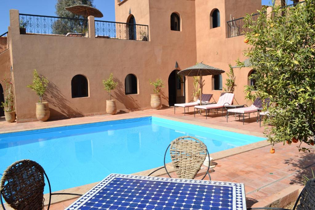 a swimming pool with a table and chairs next to a house at Riad Dar Bergui in Ouarzazate