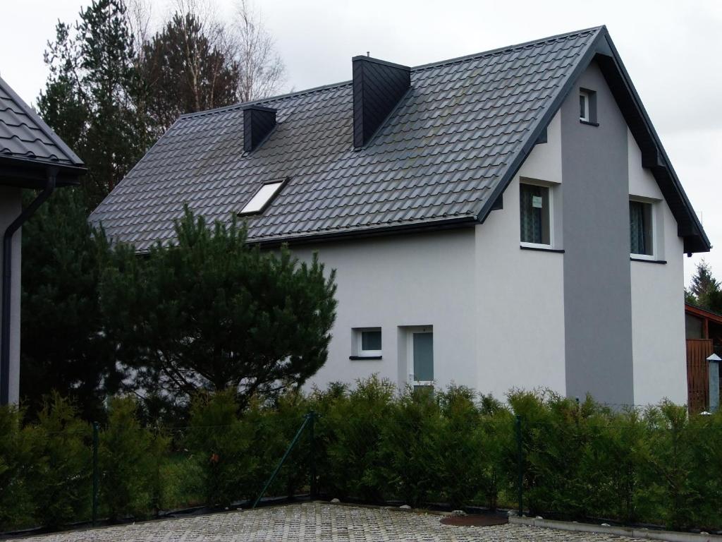 a white house with a black roof at apartamenty-segment 1 in Lubiatowo