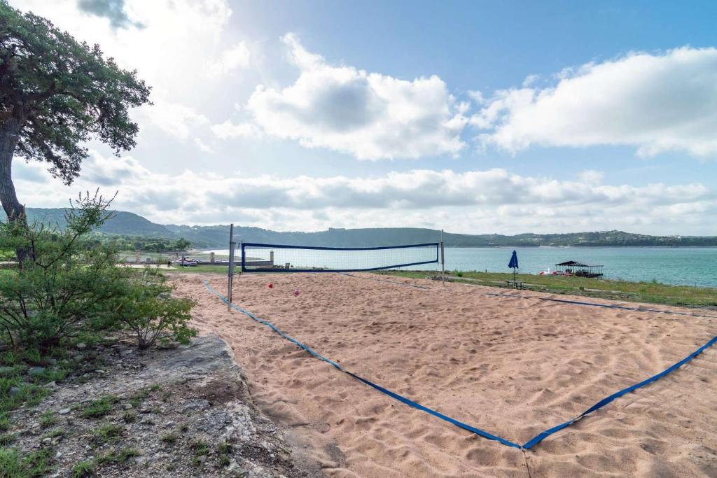 a volleyball net on a sandy beach next to the water at Comanche Trail Guest House in Volente