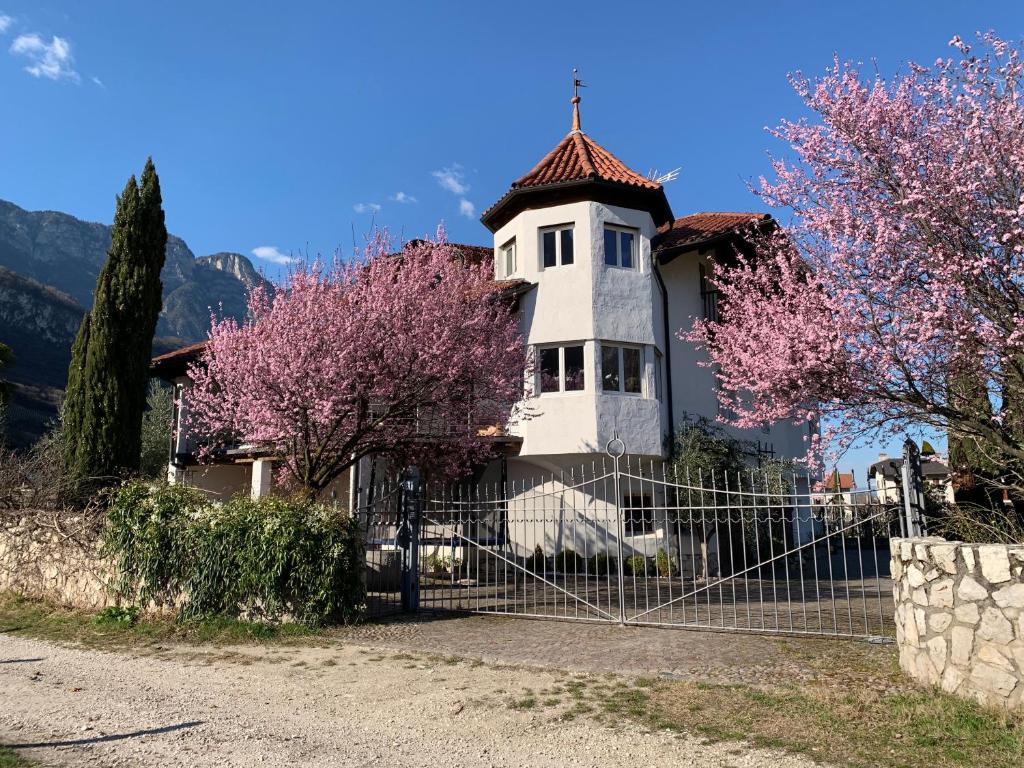 ein weißes Haus mit einem Zaun vor einigen Bäumen in der Unterkunft Ferienwohnung Eichnerhof in Margreid an der Weinstraße