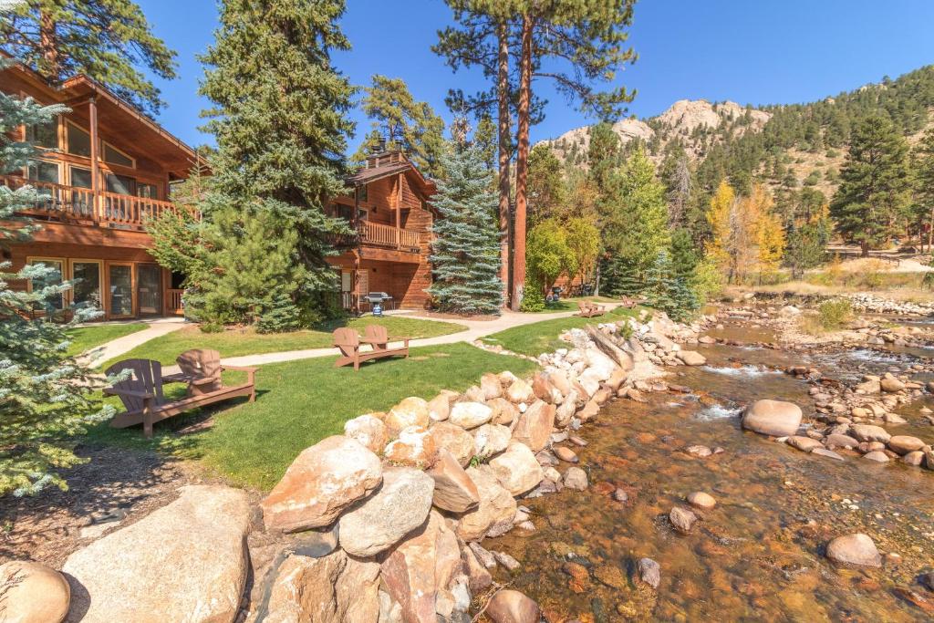 a log home with a river and a stone wall at Woodlands on Fall River in Estes Park