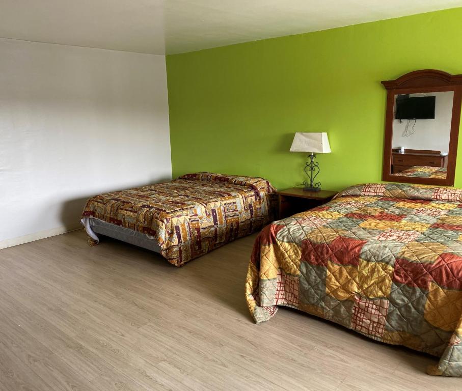 Habitación de hotel con 2 camas y espejo en Astro Motel, en San Bernardino