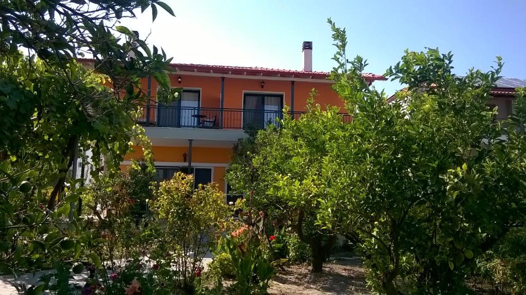 un edificio arancione con balcone dietro gli alberi di Orange Tree Garden a Pefkohori