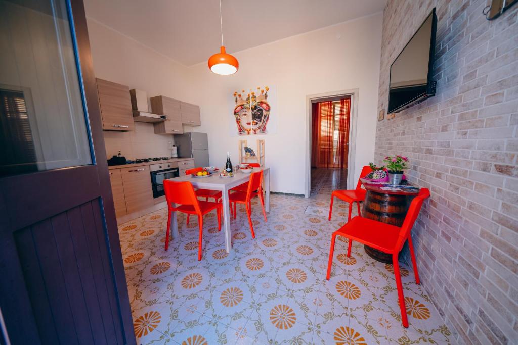 a kitchen with a table and red chairs in a room at SyracuseApartments il mare di Ortigia in Syracuse