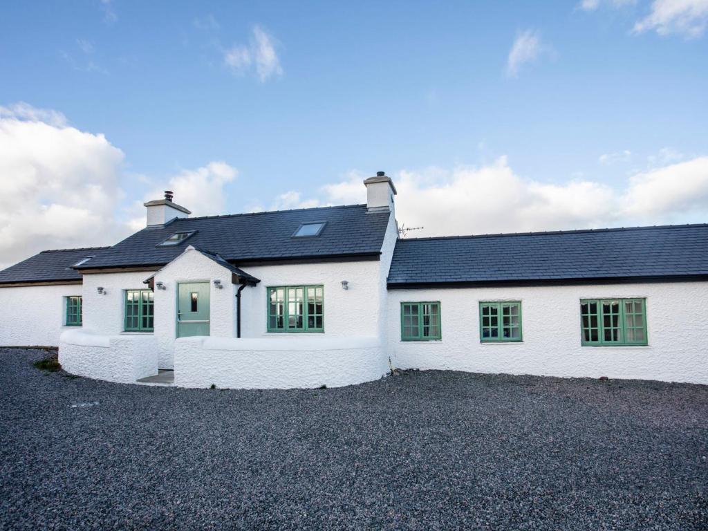 a white house with a black roof at Mwythus in Rhoscolyn