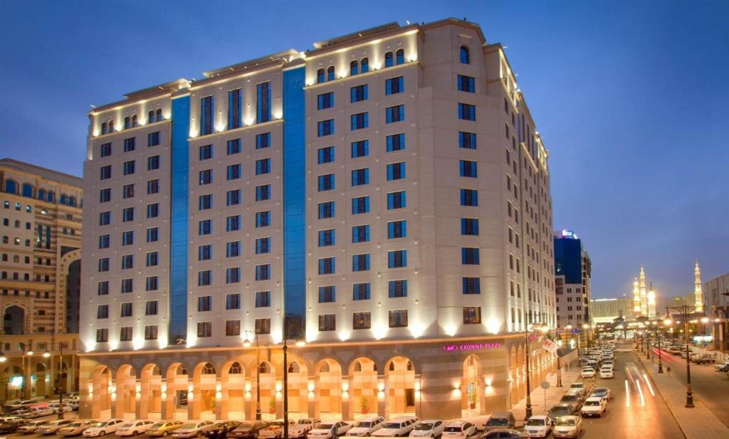 فندق كراون بلازا المدينة في المدينة المنورة: مبنى طويل وبه سيارات متوقفة في موقف للسيارات