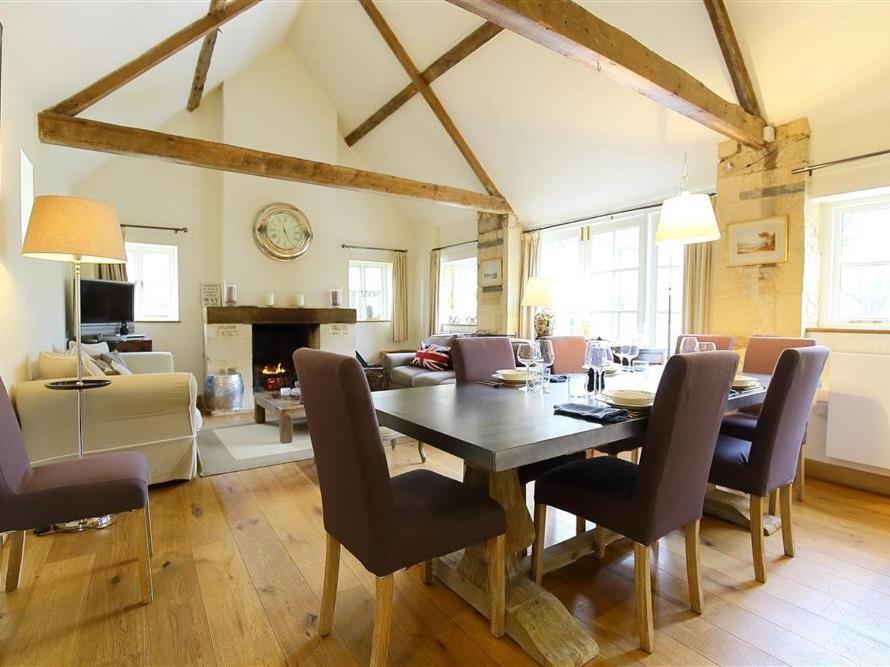 a dining room and living room with a table and chairs at Hazel Manor Wing in Miserden