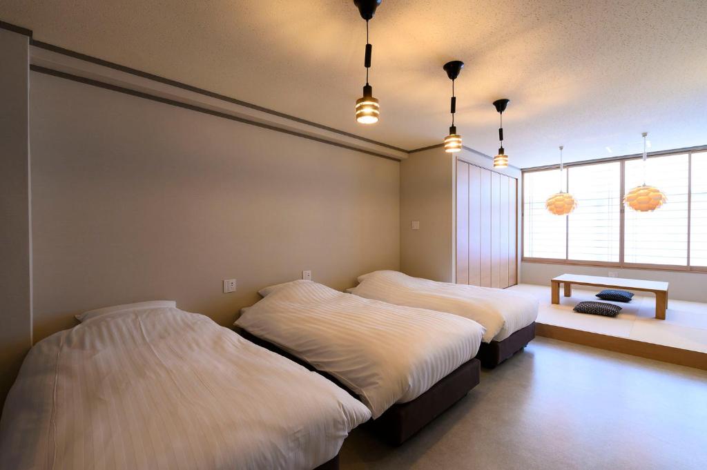 een slaapkamer met 2 bedden en een raam bij BEYOND HOTEL Takayama 3rd in Takayama