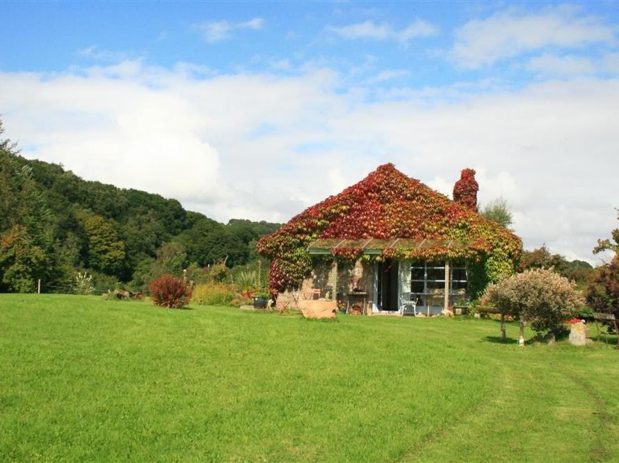 a house covered in ivy on a green field at The Piggery in Woolaston