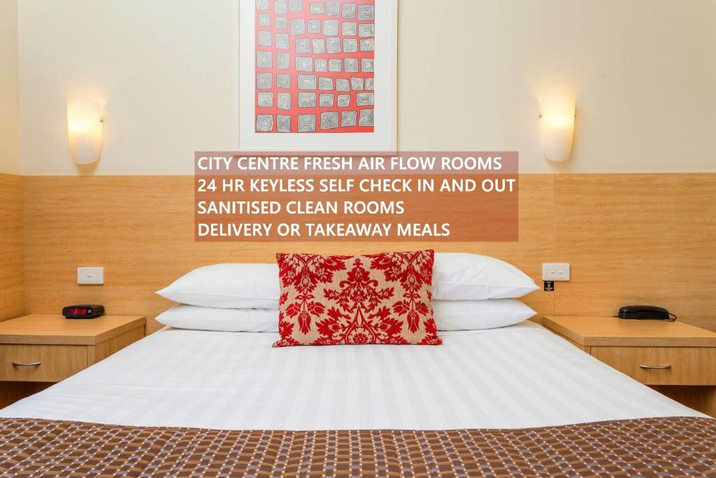 een slaapkamer met een bed met een rood kussen erop bij The Club Motel and Apartments in Wagga Wagga