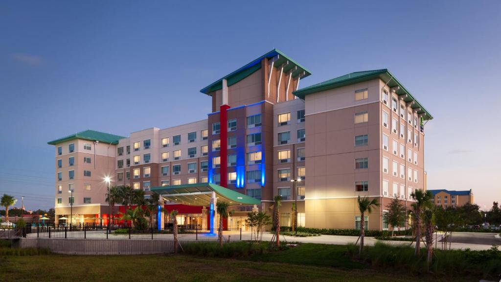 um grande edifício com uma bandeira ao lado em Holiday Inn Express & Suites - Orlando At Seaworld, an IHG Hotel em Orlando