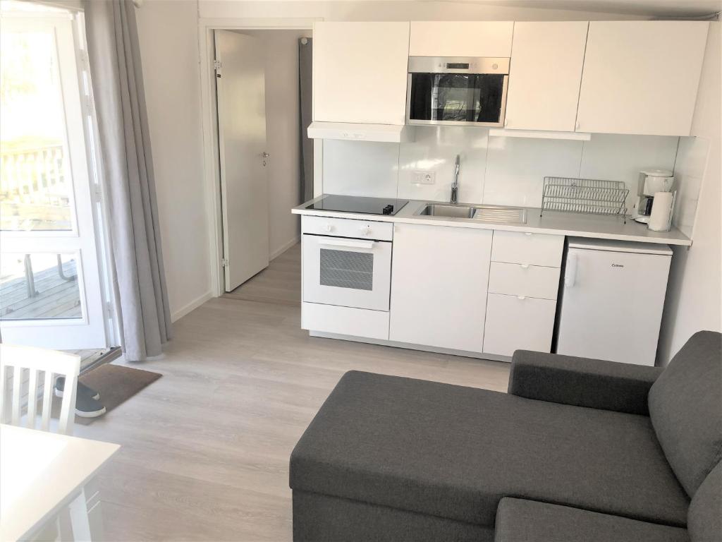 a kitchen with white cabinets and a couch in a living room at Trelleborg Strand in Trelleborg