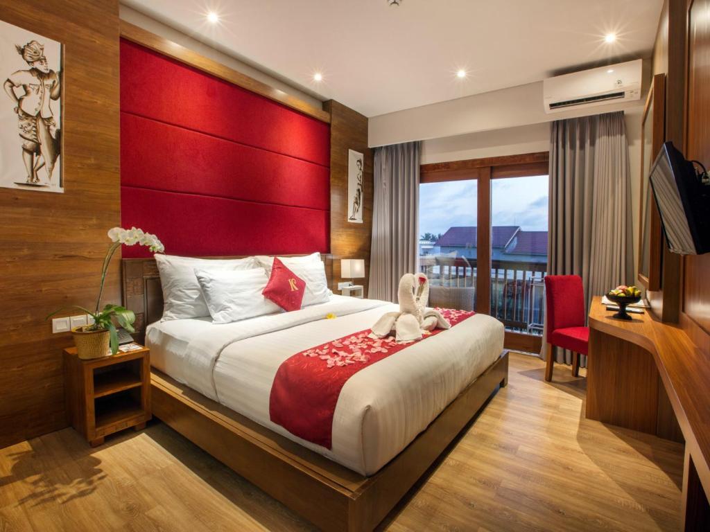 a bedroom with a large bed with a red headboard at The Kirana Canggu Hotel in Canggu