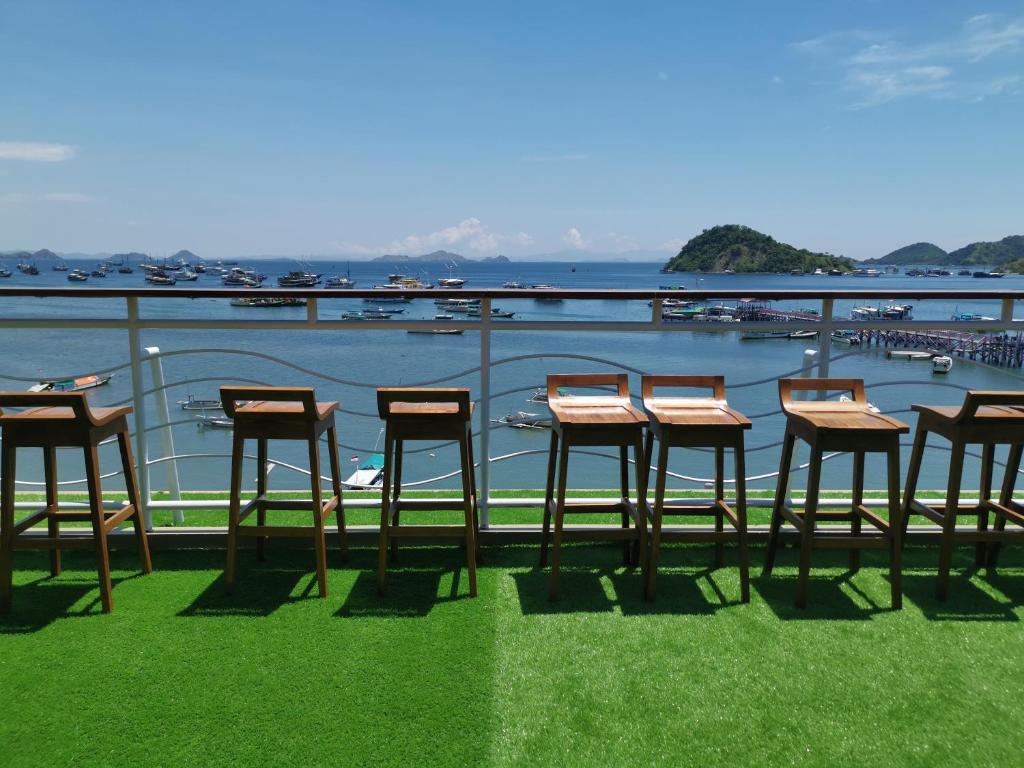 a group of chairs and tables on a balcony overlooking a harbor at Flamingo Avia Labuan Bajo in Labuan Bajo