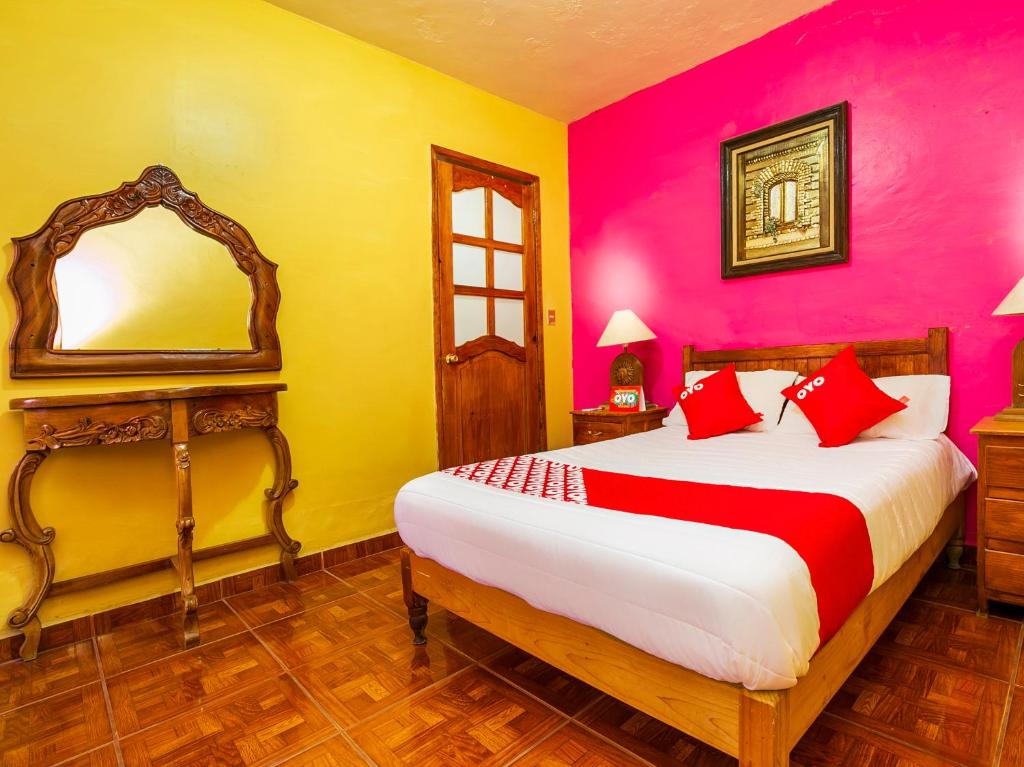 a bedroom with a bed with red and yellow walls at OYO Posada De Los Angeles, Pátzcuaro in Pátzcuaro
