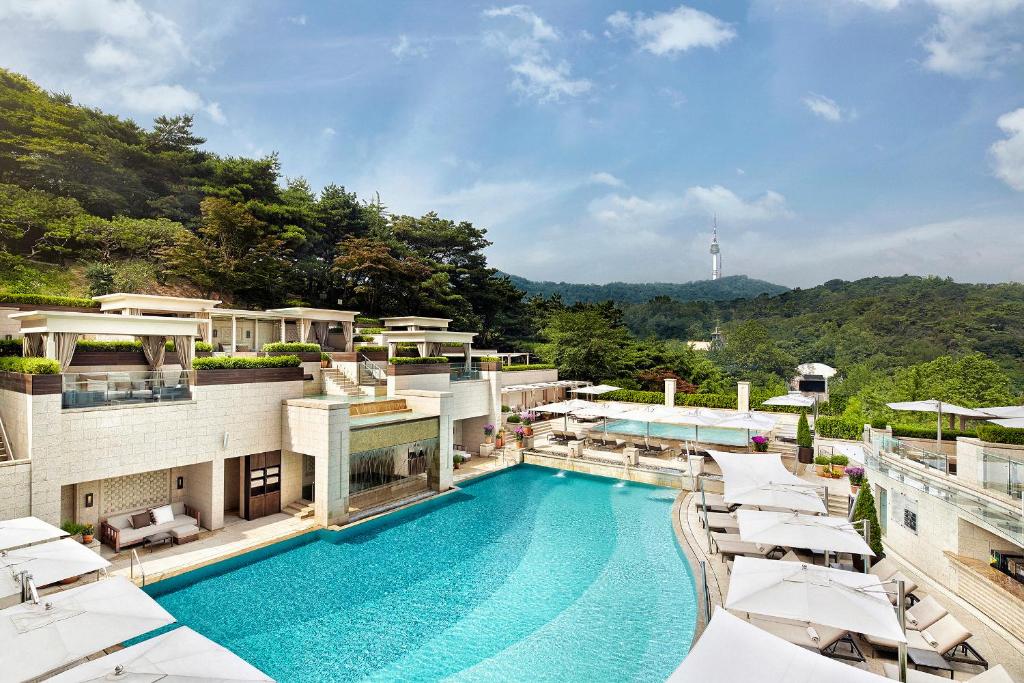 a swimming pool on top of a building with umbrellas at The Shilla Seoul in Seoul